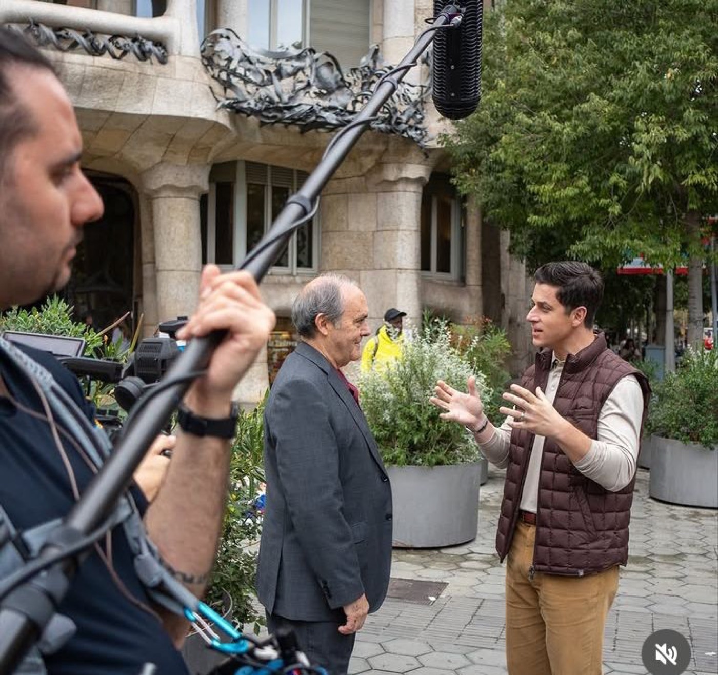José M. Almuzara es entrevistado en la calle frente a la Casa Batlló por un periodista, con un técnico de sonido sujetando una pértiga de micrófono en primer plano.